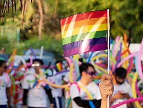LGBT pride month background. a spectator waves a gay rainbow flag at LGBT gay pride parade festival in Thailand.