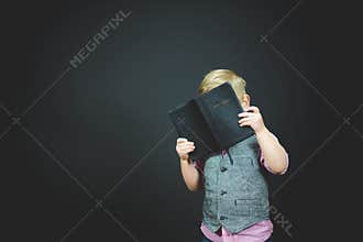 Beautiful shot of a child holding an open bible with a black background