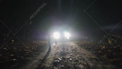Silhouette of a running girl in the headlights of a car