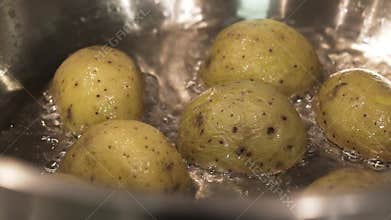Close up for brown potatoes simmering in boiling water in the saucepan, food and cooking vegetables concept. Action