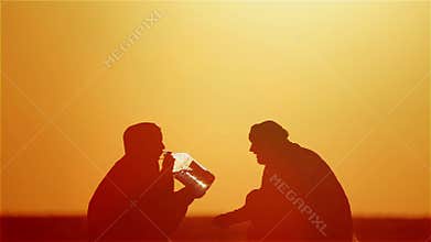Muslim couple in the desert with guns and a bottle of water.