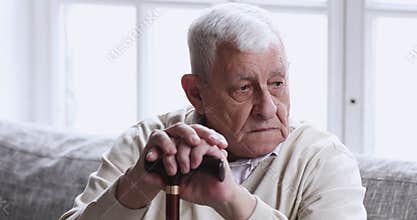 Sad old grandfather hold cane stick sit alone on couch