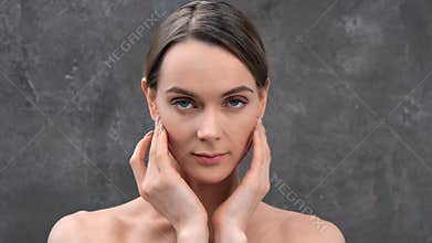 Closeup face of beauty female model smiling stroking young fresh skin looking at camera 4k