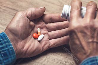Many multi-colored pills in a Senior`s hands