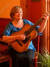 Happy senior guitarist, playing acoustic guitar.