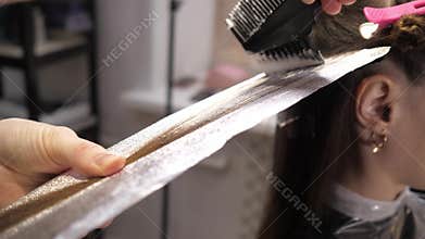 Cute girl in a beauty salon on the procedure of hair coloring. Airtouch