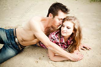 Young couple man and woman lying on sand and smiling on summer day