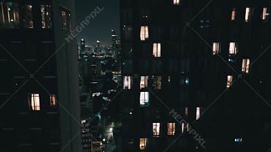 Cinematic shot luxury apartment in modern tall residential building at night. Aerial fly at night city between modern