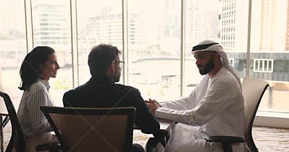 Three multicultural business partners finish successful negotiations in office