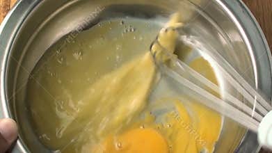 Eggs in stainless steel bowl being beaten for omelet