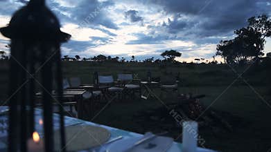 A luxury glamping camping safari dinner table Set Up with a fire at a Lodge accommodation In Kenya