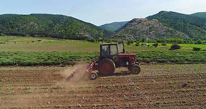 Tractor cultivating the ground in a agricultural field. Farmer preparing land for sowing