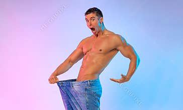 The man demonstrates problems with potency. Size matters. Young man showing how much weight he lost with big jeans. Fat