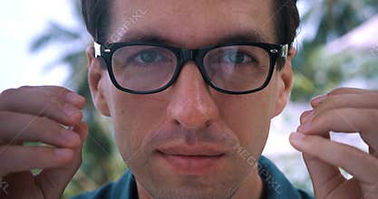 Close up man with poor eyesight puts on eyeglasses to see better outdoors. Close-up portrait man peering and can't