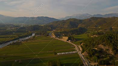 aerial scenic landscape with green fields, meadows, curved mountain river and mountain ridge with high mountains and