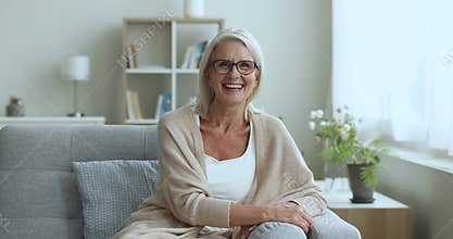 Mature woman smile pose for camera seated on sofa indoor