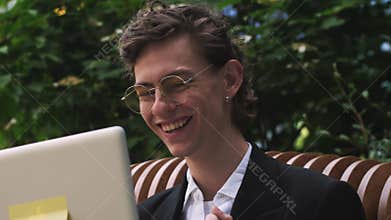 Overjoyed young businessman in formal wear and glasses looking at laptop screen, excited by unbelievable good news