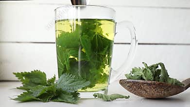 Herbal tea made of dry Urtica dioica, known as common nettle, burn nettle or stinging nettle leaves in clear glass cup.