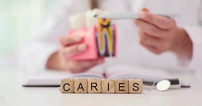 Hands of dentist and tooth with caries in dental clinic