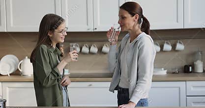 Middle-aged woman her teenage daughter holding glasses, drink water