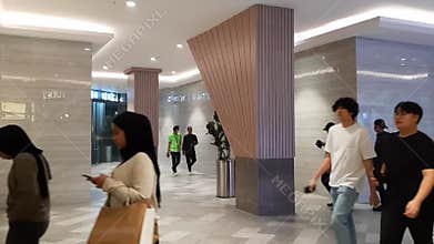 Crowd of visitors inside luxury hotel plaza mall with cream asymmetrical columns