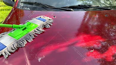 Professional car washing a red car hood with a special mop