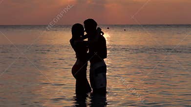 Silhouette Of Romantic Couple Kissing In Sea