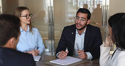 Serious confident young Middle Eastern businessman talking to coworkers