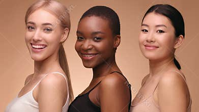 Diverse group of three women smiling together against a neutral background