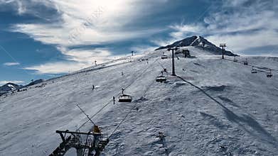Aerial view over snowy mountain winter forest with chair lift at ski resort. Ski lift cable car