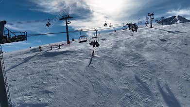 Aerial view over snowy mountain winter forest with chair lift at ski resort. Ski lift cable car top down drone shot.