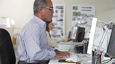 Woman Working At Desk In Busy Creative Office