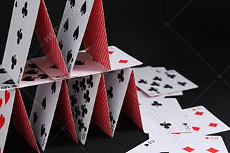 House of playing cards on black background, space for text