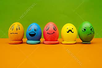 Lined Up Painted Easter Eggs With Expressive Cartoon Faces On Green and Orange Background