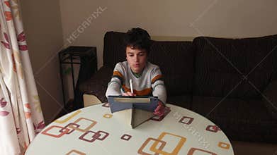 Young boy using digital tablet and stylus at home