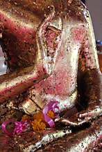 A pink ribbon and dried flowers were put on a statue of Buddha (Thailand)