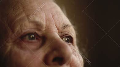 Portrait of an old lonely human who looks out the window