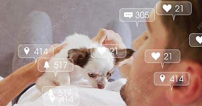 Man in white tee cradling chihuahua puppy on couch, hand petting and social media overlays floating