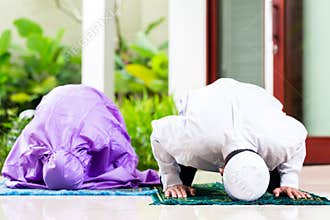 Asian Muslim couple, man and woman, praying at home