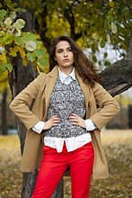 Young woman in fashion coat walking in autumn park