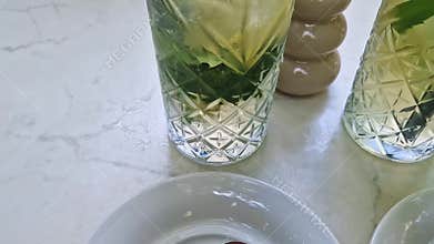 Two elegant chocolate popsicle cakes sit on the table near tall glasses of refreshing mint mojito lemonade