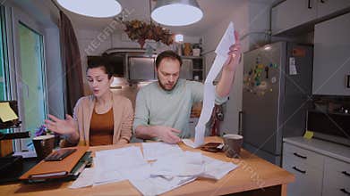 Sad young couple paying the bills. Man and woman sitting in the kitchen and sorting checks and accounts.