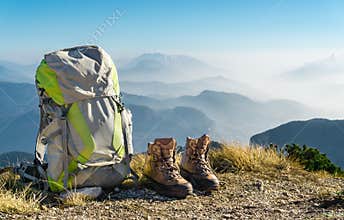 Hiking equipment. Backpack and boots on top of mountain.