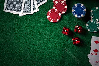 Poker chips and gamble cards on casino green table with low key