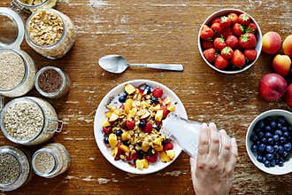 Breakfast scene hand pouring milk on muesli healthy lifestyle organic nutrition
