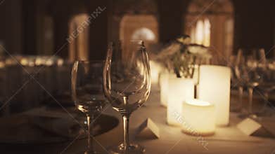 Clean wine glasses on dinner table with lit candles and plates at banquette
