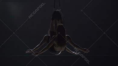 Two beautiful girls performs a trick at the aerial hoop