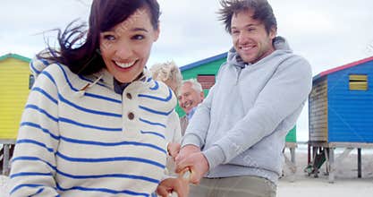 Multi generation family playing tug of war at beach