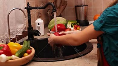 Young girl hands washing vegetables at the kitchen sink