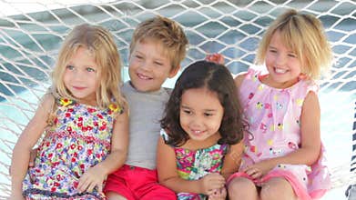Four Children Relaxing In Garden Hammock Together
